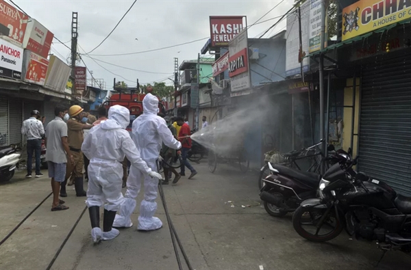 22 de junho: bombeiros usam spray desinfetante em lojas fechadas de um mercado em Shiliguri, na Índia, contra a Covid-19. (Foto: Diptendu Dutta / AFP/ Reprodução/ G1)