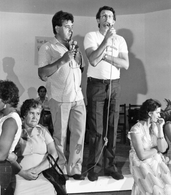 Antonio Domingos Barbon partiu recentemente para conviver entre os celestiais. Foi um homem que enfrentou muitos desafios e conquistou o respeito das pessoas que encontrou pelos caminhos. Nesta foto dos anos 80, ele ainda investido nas funções sacerdotais, como pároco da Igreja São Bento, promoveu em parceria com a RÁDIO CIDADE, uma Festa de Santos Reis. Como sempre, muito empolgado, o então padre Barbon (ao lado do radialista João Carlos Ferreira) proferiu uma mensagem aos participantes do evento, saudando as Companhia de Reis e fiéis da Paróquia. Ao fundo aparece o sonoplasta da emissora, o saudoso e sempre prestativo Isaias Pereira de Ávila.  Foto arquivo da Rádio Cidade. 