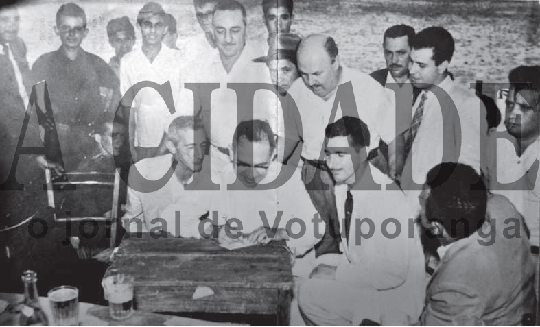 Esta foto é histórica. O ano é 1956, na semana do Natal. E com esta assinatura do deputado estadual Dr. Anísio José Moreira, que era de Mirassol, assim nasceu a extinta Associação Atlética Votuporanguense, uma das glórias do futebol do interior. Existiam na cidade dois times rivais. O VEC - Votuporanga Esporte Clube tinha como presidente o Sr. José Silva Melo (Zéquinha Alfaiate), e o América Futebol Clube, na época sob a presidência do Rachidinho (funcionário da Prefeitura Municipal). Os homens que aparecem nesta foto foram os articuladores da fusão, os responsáveis direto pelo surgimento da AA Votuporanguense. Confira a partir da esquerda quem são esses pioneiros do esporte. Em pé: Nélson Maraldi, Ozório Casado, Arquimedes Neves (o Nei), ? , Moacir Másquio (Nininho), Vicente Castrequini, Lula, Zézinho Marão, dr. Martiniano Salgado, ? , Carlos Márcio de Castro Junqueira, e Deolindo Trindade (Frinfa). Agachados na mesma ordem: o primeiro não identificado, Alfredo Rodrigues Simões (Cavaco), ao centro o deputado estadual Dr. Anísidio José Moreira, Plínio Marin, e de costas Emílio Liévana Torres (o Torrinha). 

*Confira mais desta coluna em nossa edição impressa e online para assinantes.