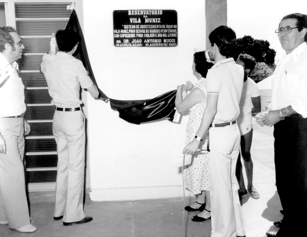 O descerramento da placa marca a inauguração do Reservatório da Vila Muniz, entregue solenemente em 10 de agosto de 1980, dentro das festividades de 43º aniversário de Votuporanga. Aparecem na foto da esquerda para a direita: o prefeito João Antonio Nucci, Frutuoso Martim Jurenti e Maria Lucinda do Nascimento Murasse (ambos de costas, descerrando a placa) o saudoso jornalista Édson Geraldo Palmiéri (também de costas) e o então vereador Joaquim Neves. A foto é do álbum de família de Ivan Ferreira do Nascimento