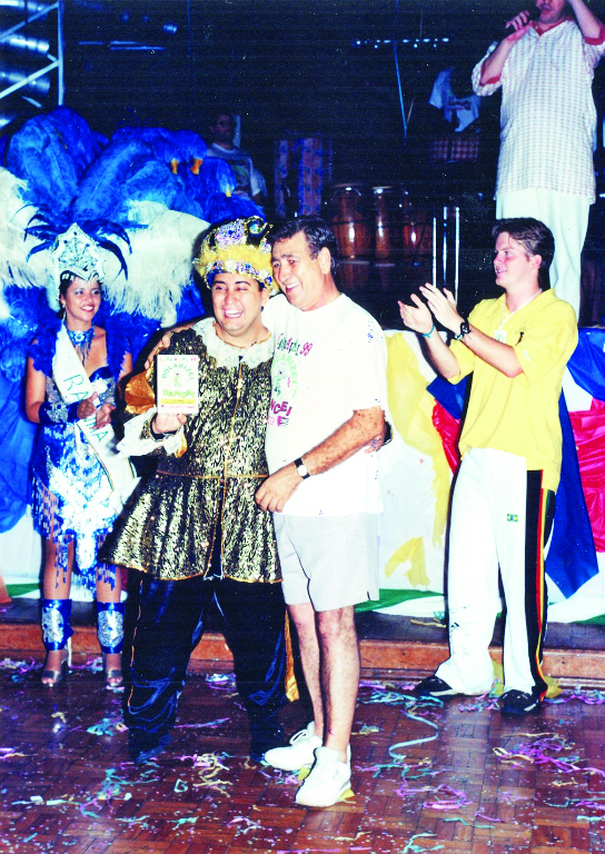 No palco do Votuporanga Clube, a partir da esquerda: Beatriz (Rainha do Carnaval), Juliano Bombom (Rei Momo), Ideval Geraldo de Freitas (presidente do Votuclube) e um intercambiário do Rotary procedente da Alemanha, batendo palmas. A foto é do arquivo de Juliano Bombom.