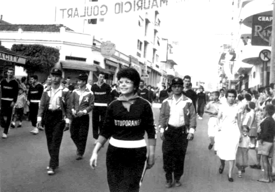 Desfile da delegação de Votuporanga na abertura dos Jogos Abertos da Araraquarense, em São José do Rio Preto, no ano de 1959. Da esquerda para a direita  pode ser identificados: Marinho Farinazzo, Aderbal Gallo, Sérgio Vicente Arroyo, Nélson Sato, professor Benedito, Sasso, Edino Commar, Eliete Gallo, Prestes, Shimiti Takahashi e Marcelo Van Haute. A foto é do arquivo de Aderbal Gallo.