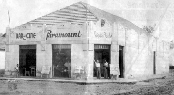 Nesta foto aparece o prédio do Bar-Cine Paramount, que pertencia aos irmãos Matta, e com o tempo, o sr. Manoel Ramalho Matta comprou a parte dos irmãos e ficou como único dono do imóvel. O Manoel Ramalho Matta no começo construiu uma olaria, para fabricar telhas, afim de acompanhar de perto  a evolução da cidade de Votuporanga. Depois, construiu na Rua Amazonas, esquina da praça central, um sobrado, onde está hoje a Giannini Sportes. Mais tarde, ele construiu 39 casas, todas de um mesmo padrão, que se denominou de Vila Matta (nas proximidades de onde está hoje a sede da Unifev). É dele também a obra de construção  do 1º cinema de Votuporanga, na continuação do sobrado que já havia erguido da esquina da praça, e que também funcionava o Bar Paramount. A área toda era de 840 metros quadrados. O primeiro cinema da cidade era de alto padrão para aquela época, uma cidade de 10 mil habitantes. O cinema, computando a parte inferior e a galeria acima, comportava confortavelmente 1.500 expectadores.\r\nE a mocidade fazia o “footing” à noite em frente ao cinema, que era o ponto de encontro dos jovens enamorados. Nos domingos e feriados, haviam os matinês-dançantes, e a bonboniere  pertencia ao saudoso Humberto Honó-rio (pai do Célio Honório). Esta é uma parte bonita da história de Votuporanga, nos bons tempos. \r\n(texto de autoria do agronômo Orlando Beretta, testemunha ocular dos fatos) Fotos da família Matta