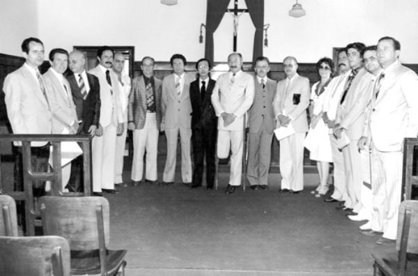 O pessoal do Cartório - Na sala do Júri, no Forum de Votuporanga, os eleitos no pleito municipal de 1982 foram diplomados pelo Juiz Eleitoral titular da Comarca de Votuporanga, Dr. Yuji Uchiyama. Confira quem são os diplomados eleitos a partir da esquerda: vereadores Ozório Casado, Walter Peresi, Milton Lisboa, Arnaldo Santa Fé Trindade,  Mehde Meidão Kanso,  o titular do Cartório Eleitoral Heitor D´Avóglio, e o eleito vereador dr. Wilson Roncatti. Ao centro, o Juiz Eleitoral  e o prefeito eleito Mário Pozzobon e o vice-prefeito eleito Rames Cury, seguido dos vereadores: José Nunes Pereira, Luzia Câmara Romani, Antenor Parisi, Élcio Gonzales Lopes, Jerônimo Figueira da Costa Filho e Alzimiro Brantis.A foto é do álbum do vice-prefeito Rames Cury.