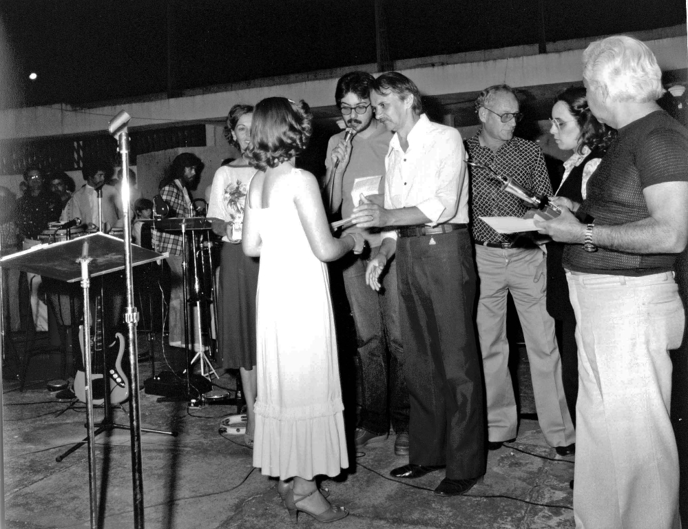 O saudoso presidente da Câmara, Otaviano Nogueira, nesta foto, faz a premiação no palco da Concha Acústica. O registro é dos anos 70, quando Votuporanga realizava durante a administração do prefeito João Antonio Nucci, a Semana da Cultura que revelava os talentos locais. Aparecem na foto o radialista José Antonio (Rádio Cidade), o então chefe de gabinete Reynaldo Zaccara Campos e o jornalista e escritor Edward Corurupe Costa. 