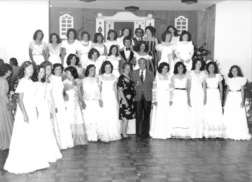 As debutantes - Em nossa coluna, mais uma foto das Debutantes do Votuporanga Clube. Veja, ao fundo, o cenário de uma decoração que transformou o palco do clube. Aliás, o Votuclube primava por três grandes investimentos em cada edição do Baile das Debutantes: a contratação da banda musical de maior evidência no país; do artista, geralmente o galã de maior prestígio na novela do momento, e uma rica e deslumbrante decoração. Os três itens garantiam o sucesso do evento. Nesta foto, aparece ao centro, o ator de novelas Flávio Galvão e os casais paraninfos. A foto é do arquivo pessoal de Rames Cury, o presidente do Votuclube na época.
