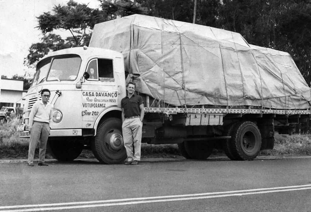 Esta foto é de 1965. Um caminhão da Casa Davanço, pilotado pelo Wanderley Parisi, assumiu o transporte da mudança de residência de Luizinho Sato para a cidade de Jundiaí. No momento da partida, caminhão carregado e coberto, Sato fez questão de uma fotografia como despedida. Wanderley Parisi guardou a foto em seu arquivo pessoal como recordação. E diz que não esquece “aquele dia”. 