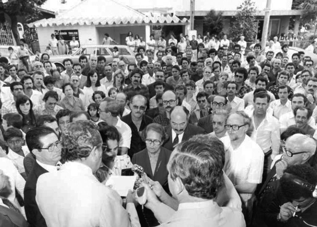 Uma bela fotografia do público que compareceu ao ato de inauguração do Edifício Julieta, um marco histórico para a era do crescimento vertical da cidade. O então prefeito João Antonio Nucci (que aparece de costas) faz o seu discurso tendo ao seu lado o vereador Joaquim Neves. Na frente dele, o dono do empreendimento Mário Pozzobon e lideranças políticas da época como o professor Ederval Gregório, José Nunes Pereira e o Dr. Joaquim Figueira da Costa. Na plateia, as personalidades conhecidas da época, onde quase todos são facilmente identificados. Esta foto pertence ao arquivo pessoal de Rames Cury.