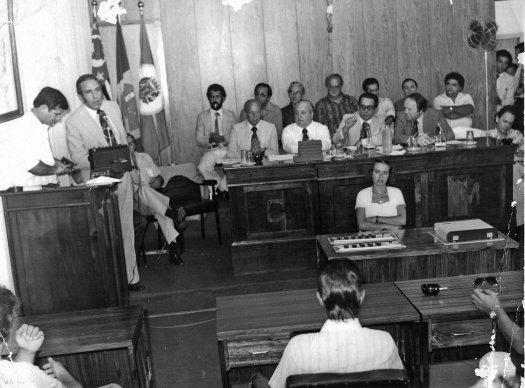 Em concorrida reunião na Câmara Municipal, no prédio da Prefeitura, onde hoje está o gabinete do prefeito, autoridades visitantes foram homenageadas. Na tribuna, discursa o então prefeito João Antonio Nucci (ao lado do vereador Alzimiro Brantis) e na mesa central aparecem deputado Waldemar Lopes Ferraz, senador Amaral Furlan, o vice-prefeito Onofre de Paula, o então vice-governador José Maria Marim e o então deputado estadual Alvaro Fraga. Na segunda fileira: Antonio Benedito Malvas, dr. Antonio Fontes, ? , Fernando Vendramini (Mirassol), outros dois não identificados e o juiz de direito Antonio Correia. Na frente, modulando o som ambiente, a funcionária Vera. A foto é do arquivo do jornal A Cidade