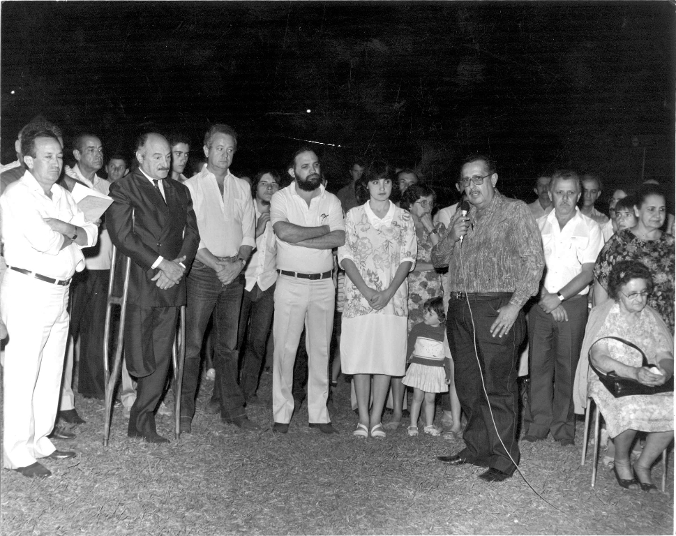 O saudoso Juvenal Domingos Martins Lopes, presidente do Sindicato Rural de Votuporanga, discursa numa cerimônia prestigiada pelas lideranças políticas dos anos 80. Da esquerda para a direita: Granada, o prefeito Mário Pozzobon, o engenheiro Jesus Silva Melo, Dr. Jerônimo Figueira da Costa Filho (na época diretor do ERG - Escritório Regional de Governo), Márcia Pozzobon Figueira, o orador, o então vice-prefeito Rames Cury e a senhora Maria Muro Pozzobon. Não consta o local da cerimônia.