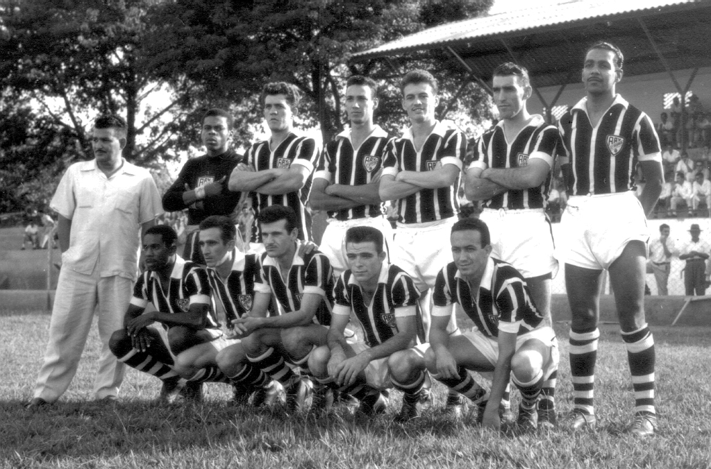 Aí está para a apreciação dos leitores, uma das primeiras formações da AA Votuporanguense. A equipe estava nascendo para a disputa da terceira divisão do Campeonato Paulista. Essa foto foi colhida no Estádio Plínio Marin e apresenta ao fundo a velha arquibancada coberta. Confira a escalação do time, da esquerda para a direita, de pé: Basílio (diretor), Cesário, Neri, Jurani, Nardinho, Baguinho e Gabriel. Agachados: Carangola, Luizinho, Lupércio, Lima e Granadinha. A foto pertence ao arquivo de Luiz Carlos Murasse