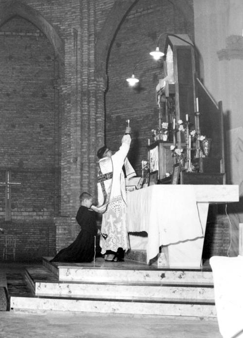 No altar - Frei Arnaldo Maria de Itaporanga celebrando Missa (momento da consagração)  na Igreja Matriz Nossa Sra. Aparecida. A foto é dos anos 60 e a celebração obedecia o ritual antigo - antes do Concilio Vaticano II com a figura do coroinha e o sacerdote  de costas para os fiéis.Detalhe: as paredes da Igreja ainda estavam sem o reboco.