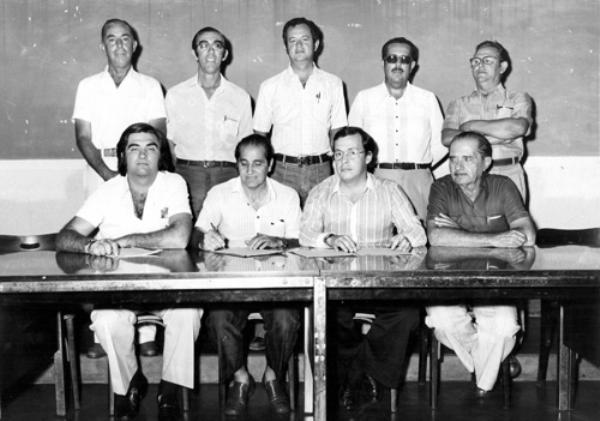 Assinatura de contrato do Frigorífico 4 Rios - Observe que quem tem a caneta na mão é o empresário Nasser Marão. Esta é uma foto histórica do ano de 1973. Foi o ato da assinatura do maior contrato para a construção do Frigorifico 4 Rios S. A.  A empresa contratada foi a Madef S.A, com sede no Rio Grande do Sul, e neste ato representada por dois dos seus engenheiros diretores. De pé, a partir da esquerda: os diretores do empreendimento, Herculano Beretta, Orlando Beretta, engenheiro Jesus Silva Mello, Juvenal Domingues Martins Lopes e Antonio Nogueira. Sentados: um dos engenheiros da Madef, o diretor presidente Nasser Marão (assinando o contrato), outro diretor da Madef, e Salvador Castrequine. A construção do Frigorifico 4 Rios foi uma arrancada para o progresso de Votuporanga nos anos 70. Registro do Foto Votuporanga de Takeo Sato e Irmãos.