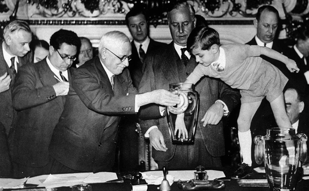 França 1938: No sorteio do Mundial de 1938, realizado em Paris, coube ao bisneto do então presidente da Fifa, Jules Rimet, a retirada das bolinhas do pote.O garoto era tão pequeno que precisou ficar em pé sobre a mesa para colocar a mão dentro dos potes. Rimet deu nome à taça da Copa do Mundo de 1946 até 1970, ano em que ela foi conquistada definitivamente pelo Brasil. Aqui, acabou roubada e derretida em 1983