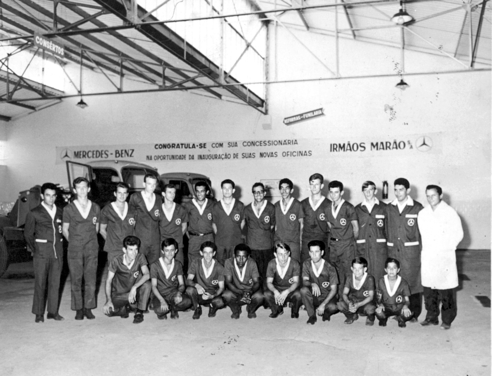 A foto é dos anos 70 quando a concessionária Mercedes Benz pertencia a empresa Irmãos Marão e atendia com loja e oficina no centro da cidade, na rua Amazonas. Veja quem trabalhava na empresa Mercedes naquela época. Acompanhe da esquerda para a direita, de pé: Orlando, Ivo, Ismael, Fiori, Domingos, Onézio, Waldir, Jacir, Tiburcio, Aderson, Waldir, Alcides, Décio e Ìtalo. Agachados na mesma ordem: Mirim, Lobo, Geraldo, Floriano, Biriba, Nardo, Dorival e Freire. A foto pertence ao arquivo familiar de Alcides Coelho.