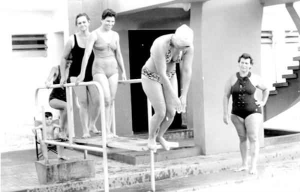 Aulas de natação - Guaracy Camargo Pignatari (à direita) falecida recentemente, era a professora de natação na conhecida Escola da Baleia do Votuporanga Clube. Nesta foto ela acompanha no trampolim o momento do mergulho de uma de suas alunas. Aparecem na sequência, Maura da Silva Comar e Rogéria (logo atrás). A foto é do dia 5 de maio de 1973.