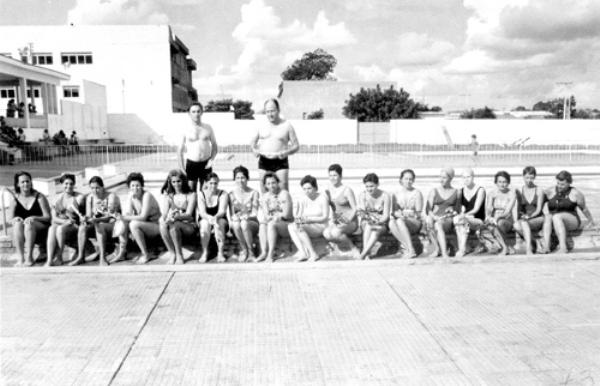 Escola da Baleia - Esta foto é do dia 5 de maio de 1973. O Votuporanga Clube congregava as senhoras da sociedade que praticavam natação. Era uma versão da Escola do Peixinho, destino às crianças. Entre elas estavam: Alice Aida de Melo, Adélia Nogueira, Maria de Lourdes Z. Regonato, Josefina Homsi Bernardes, Maura da Silva Comar, Ivanilde R. Waideman, Ione Parra, Guaracy Camargo Pignatari, Maria Cristina Marão, Vilma de Carvalho e Fany Pereira Barbieri. Em pé, Reinaldo Parra Bariani e Ismael Moraes. A foto pertence ao arquivo da senhora Maura da Silva Comar.\r\n 