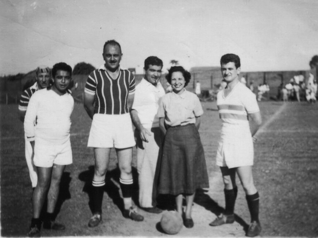 Esta é uma foto interessante e muito rara. Segundo o remetente, trata-se de um momento de um jogo de futebol nos anos 50. O jogador é o Affonso, que chegou em Votuporanga em 1950. A foto deve ter sido colhida naqueles dias. A “madrinha” se chama Oneide, e era professora no ginásio estadual. Rachid Homsi aparece no esplendor da sua mocidade, nem tinha cabelos brancos ainda. A foto pertente a João Gualberto e Marília