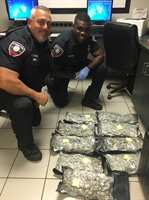 Os policiais Jon Cusack e Peterson Jacques ao lado da mala com a erva (Foto: Pembroke Pines Police Department/Facebook)