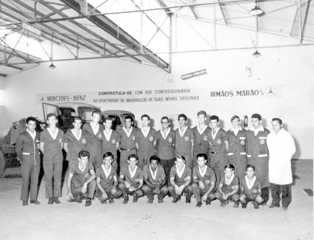 A foto é dos anos 70 quando a concessionária Mercedes-Benz pertencia a empresa Irmãos Marão e atendia com loja e oficina no centro da cidade, na rua Amazonas. Veja quem trabalhava na empresa Mercedes naquela época. Acompanhe da esquerda para a direita, de pé: Orlando, Ivo, Ismael, Fiori, Domingos, Onézio, Waldir, Jacir, Tiburcio, Aderson, Waldir, Alcides, Décio e Ítalo. Agachados na mesma ordem: Mirim, Lobo, Geraldo, Floriano, Biriba, Nardo, Dorival e Freire